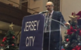 Rabbi at podium with sign that says "Jersey City"