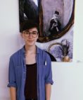 headshot of Emma Gelbard inside a gallery in front of one of her paintings