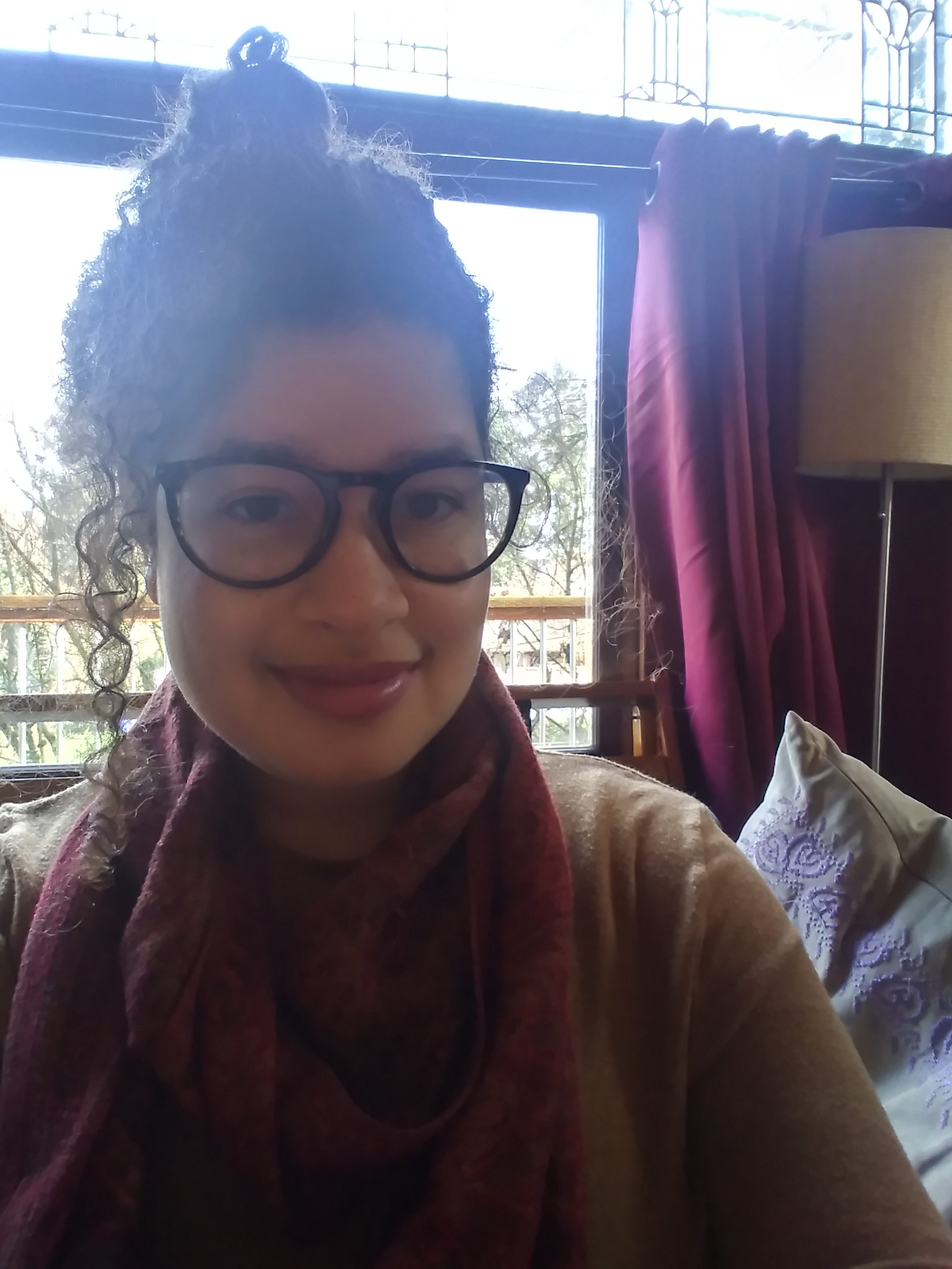 photo of Jennifer Kemp in front of a window, curtains and a lamp can bee seen on the right