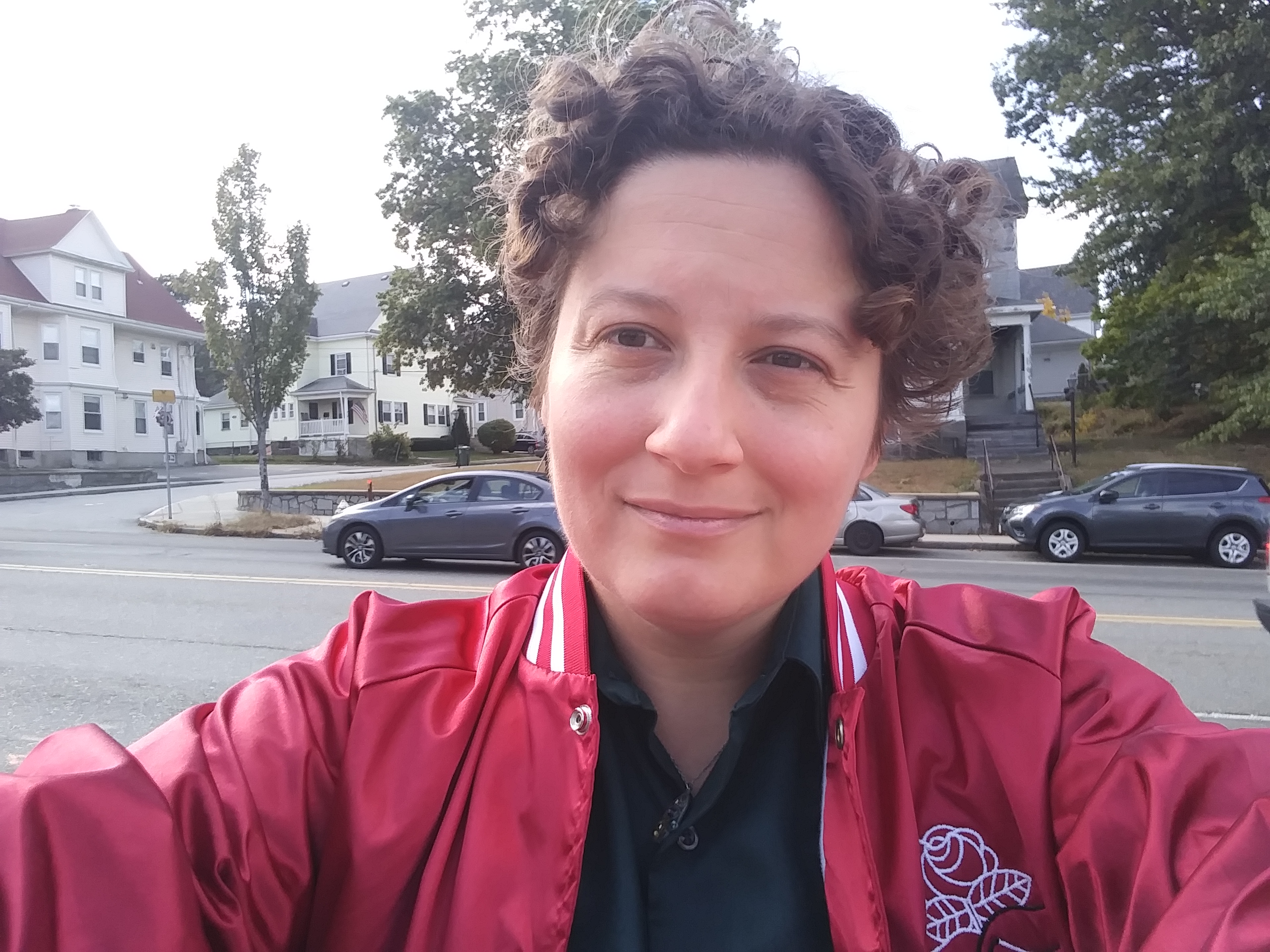 selfie of Jessie Lowell standing outside where houses and cars on a street can be seen behind