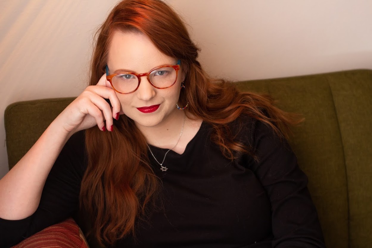 headshot of Stephanie Gray sitting on a green couch with a pink wall behind