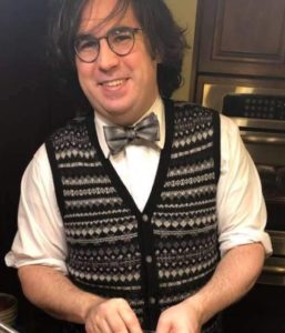 photo of Justin Callis, a long haired man in a vest and a bowtie