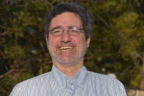 Image Description: headshot of Meir Lakein, a white man wearing striped shirt and glasses smiling