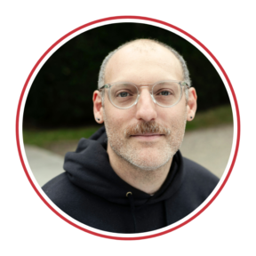 Headshot of David Schwartz, a white man wearing glasses and a black hoodie. 